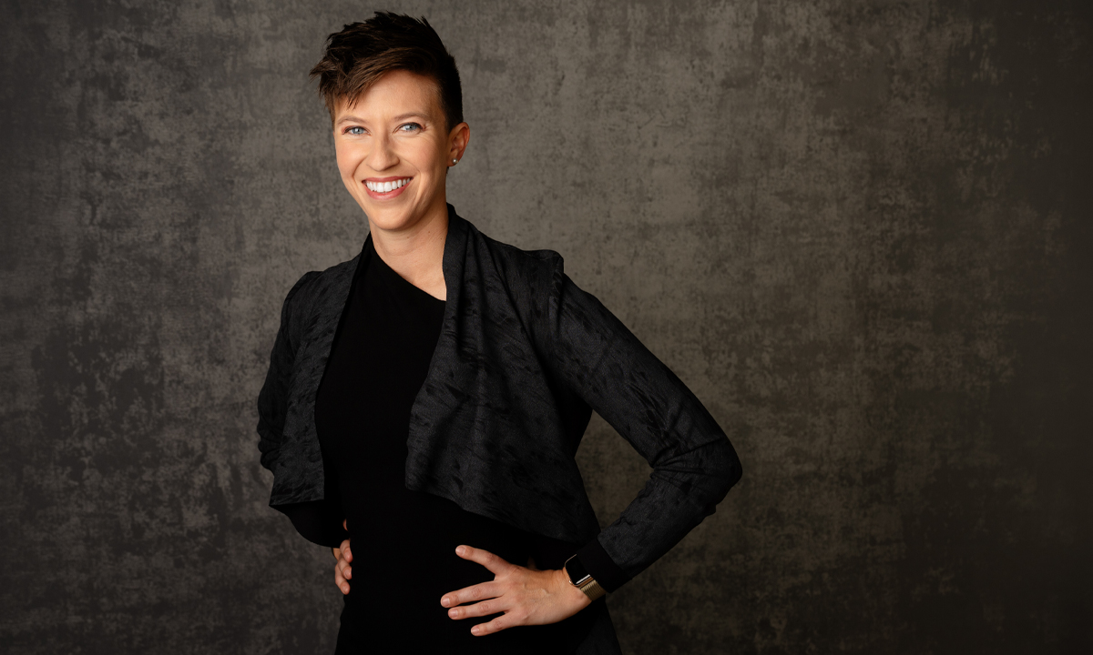 Woman in black in front of a black speckled wall for a corporate headshot